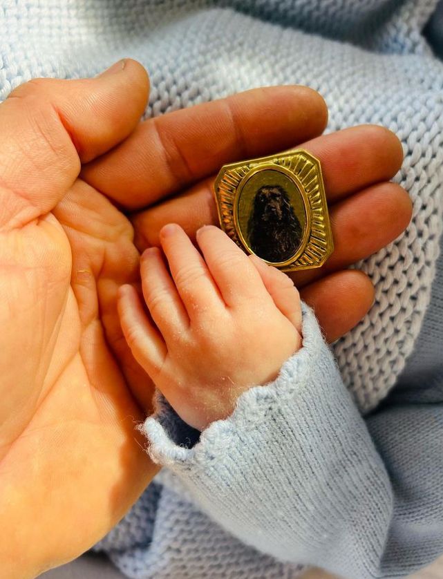 A baby hand with a pendant featuring a dog